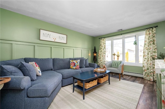 living area with a baseboard radiator, visible vents, a decorative wall, wainscoting, and wood finished floors