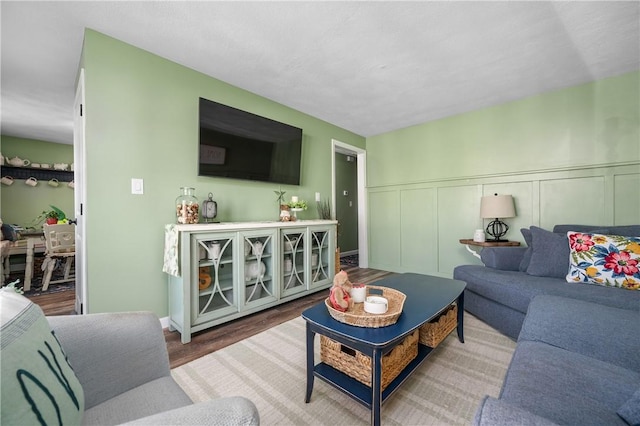 living area featuring wainscoting, wood finished floors, and a decorative wall