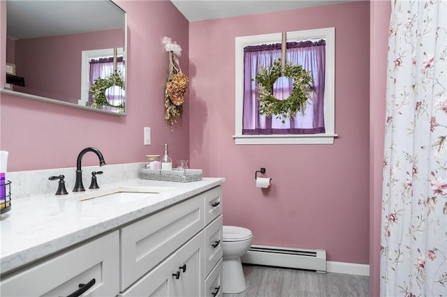 full bath featuring baseboards, toilet, vanity, and baseboard heating