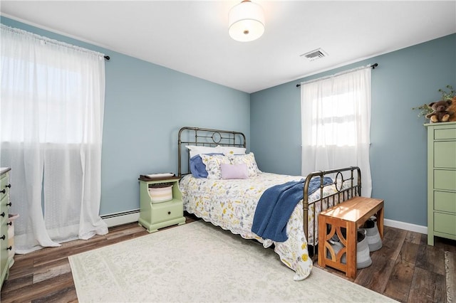 bedroom with baseboards, a baseboard radiator, visible vents, and wood finished floors