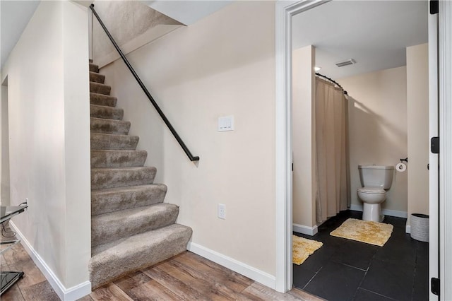 stairway featuring visible vents, baseboards, and wood finished floors