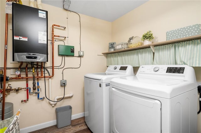 laundry area featuring laundry area, wood finished floors, baseboards, water heater, and independent washer and dryer