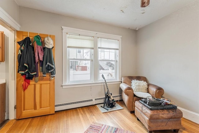 living area with light wood-style floors and a baseboard heating unit