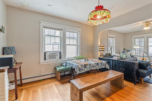 dining space featuring arched walkways, a baseboard radiator, light wood-style flooring, a textured ceiling, and cooling unit