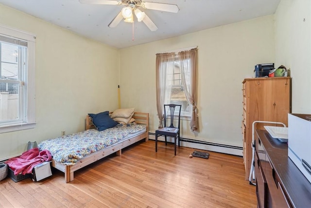 bedroom featuring light wood-style floors, multiple windows, and a baseboard heating unit