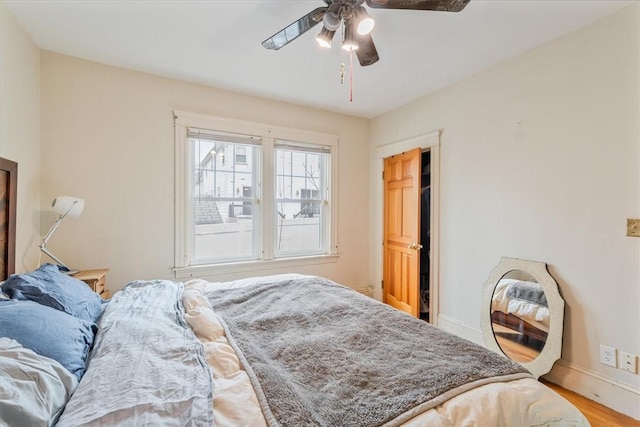 bedroom with a ceiling fan, baseboards, and wood finished floors