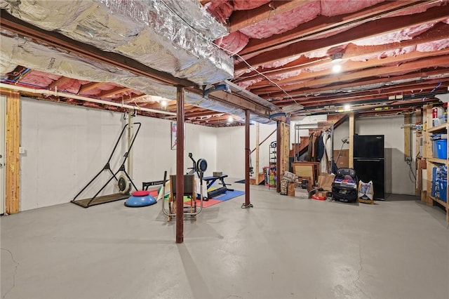 unfinished basement featuring freestanding refrigerator