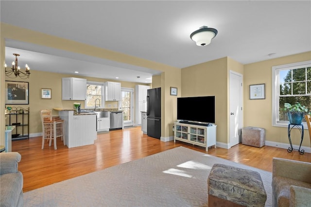 living area with a notable chandelier, recessed lighting, baseboards, and light wood finished floors