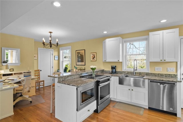 kitchen featuring a peninsula, light wood-style flooring, a sink, white cabinets, and appliances with stainless steel finishes