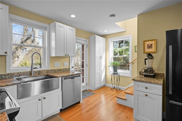 kitchen with dishwasher, light wood-style flooring, freestanding refrigerator, plenty of natural light, and a sink