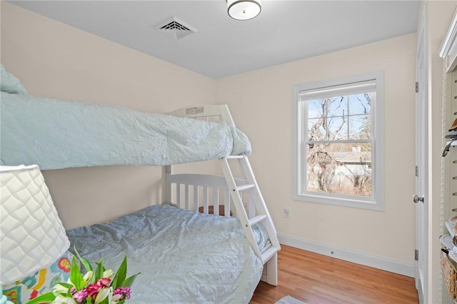 bedroom with wood finished floors, visible vents, and baseboards