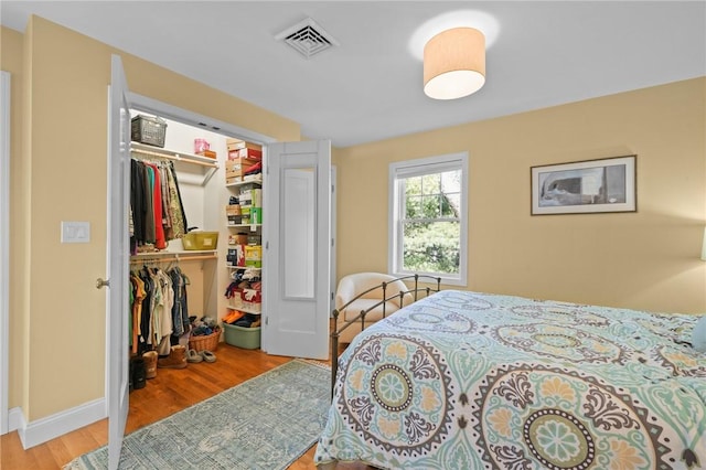 bedroom with visible vents, baseboards, a closet, and wood finished floors