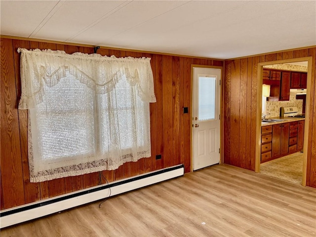 interior space featuring a healthy amount of sunlight, wood walls, a baseboard radiator, and wood finished floors