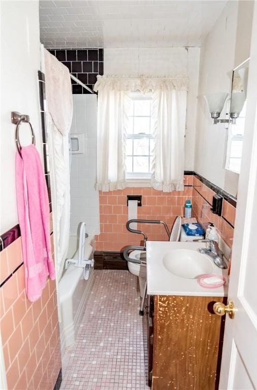 bathroom with tile patterned floors, shower / bathtub combination with curtain, toilet, tile walls, and vanity