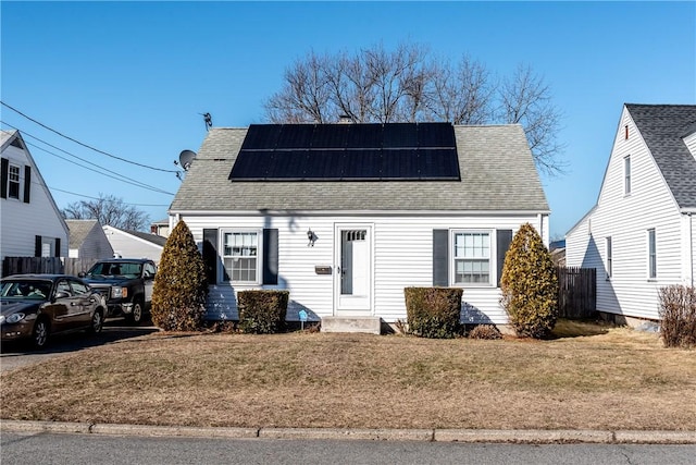 view of front of house with solar panels, a front lawn, and roof with shingles