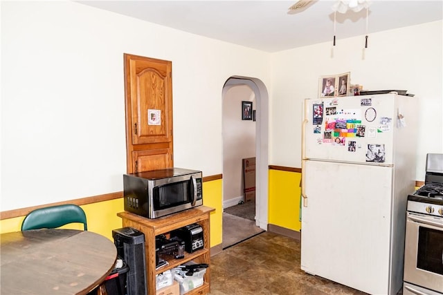 kitchen featuring arched walkways, appliances with stainless steel finishes, baseboards, and ceiling fan