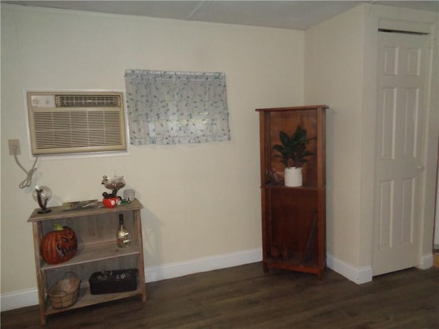 living area featuring a wall mounted air conditioner, wood finished floors, and baseboards