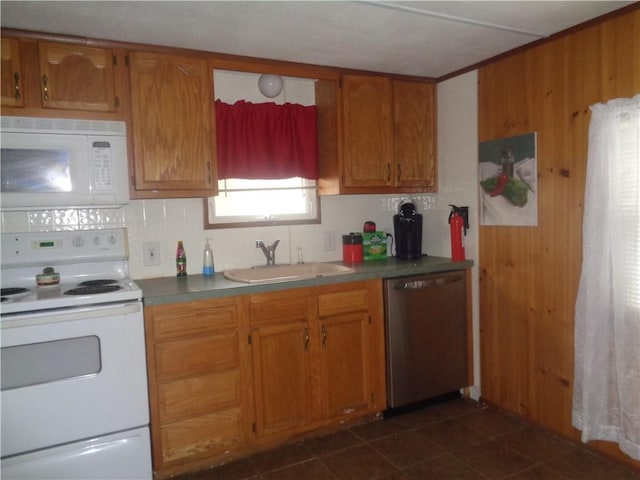 kitchen featuring white appliances, dark tile patterned flooring, a sink, decorative backsplash, and brown cabinets