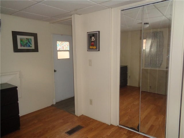 hall featuring visible vents, a drop ceiling, and wood finished floors