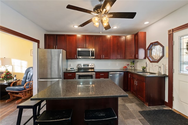 kitchen featuring a center island, stainless steel appliances, recessed lighting, a sink, and dark brown cabinets