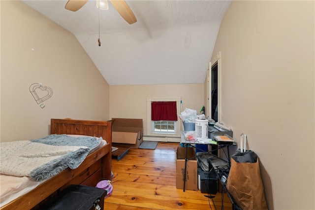 bedroom featuring lofted ceiling, hardwood / wood-style flooring, ceiling fan, and baseboard heating