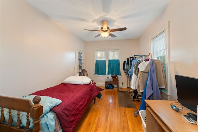 bedroom featuring multiple windows, light wood-type flooring, a ceiling fan, and baseboards