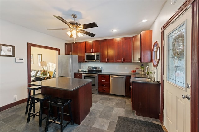 kitchen featuring dark countertops, a breakfast bar, stainless steel appliances, dark brown cabinets, and a sink