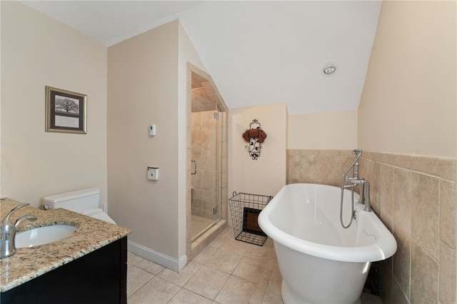 bathroom with a stall shower, a soaking tub, tile patterned floors, vanity, and tile walls