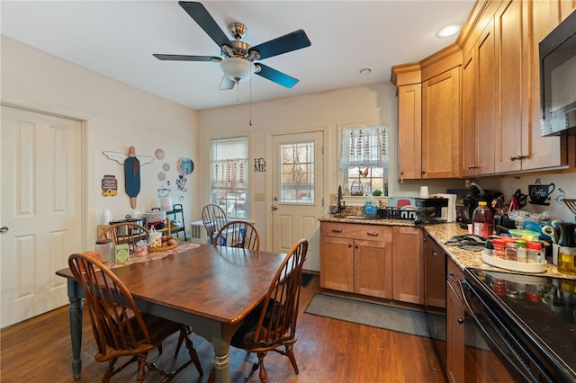 kitchen with a ceiling fan, dark wood-style flooring, black appliances, and light stone countertops