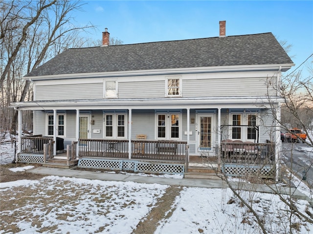 view of front of home featuring covered porch, a chimney, and roof with shingles