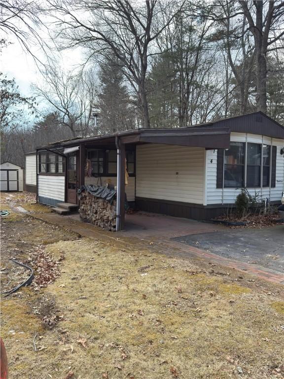 view of front of home featuring a carport, an outdoor structure, driveway, and a storage shed