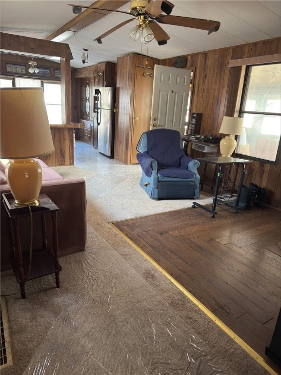 living area with wooden walls and a ceiling fan