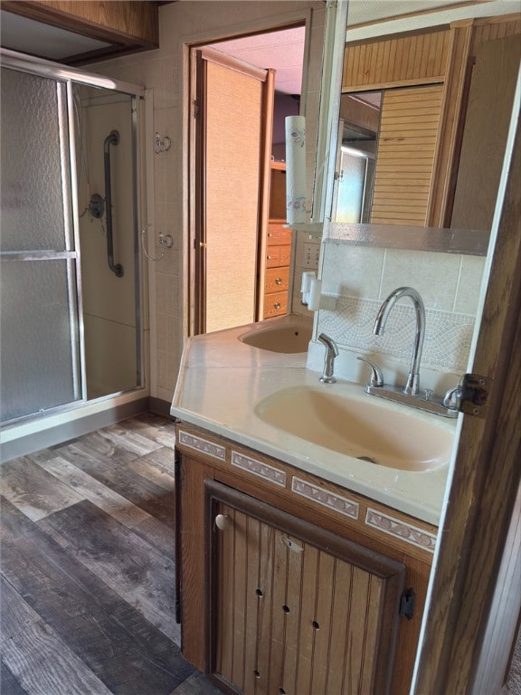 bathroom with a stall shower, vanity, decorative backsplash, and wood finished floors