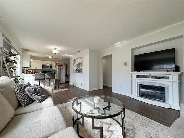 living area with dark wood-style floors, baseboards, a high end fireplace, and crown molding