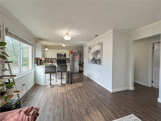 kitchen featuring stainless steel appliances, a peninsula, white cabinets, dark wood-style floors, and crown molding