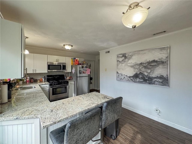 kitchen with crown molding, stainless steel appliances, visible vents, a sink, and light stone countertops