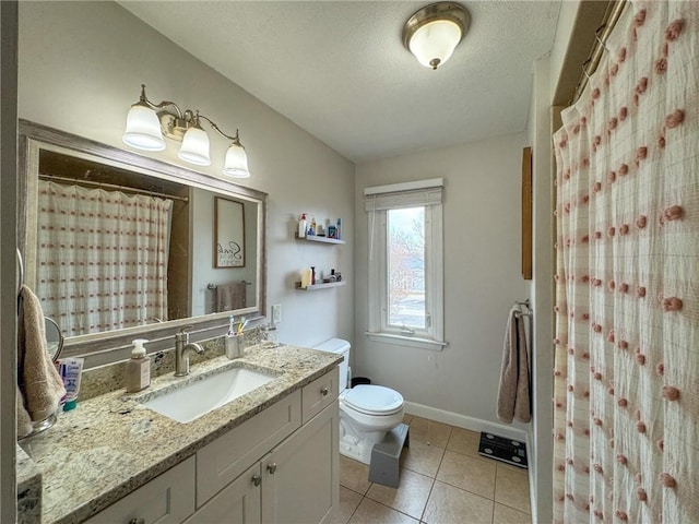 bathroom with a textured ceiling, toilet, vanity, baseboards, and tile patterned floors