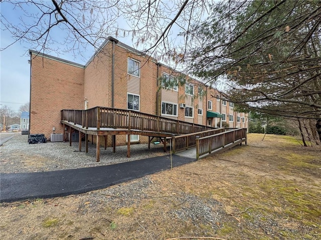 back of house featuring central AC unit and brick siding