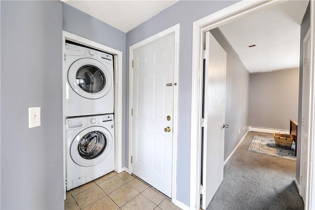 laundry room with light tile patterned floors, a baseboard heating unit, stacked washer and dryer, light carpet, and laundry area