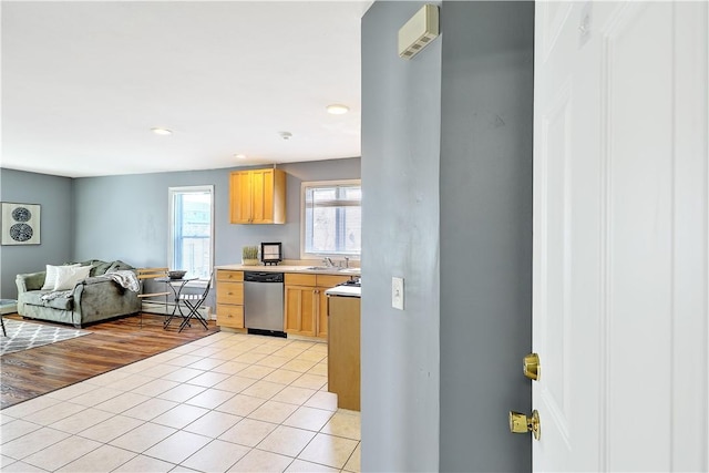 kitchen featuring light tile patterned flooring, a sink, open floor plan, light countertops, and stainless steel dishwasher