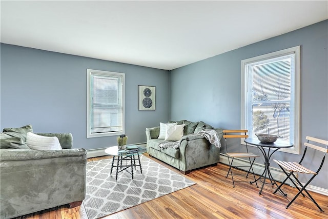 living area featuring a baseboard radiator, baseboards, baseboard heating, and wood finished floors