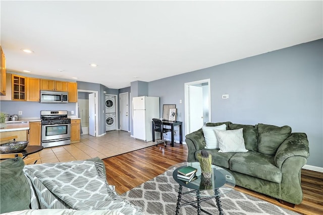 living room featuring baseboards, stacked washer and dryer, recessed lighting, and light wood-style floors