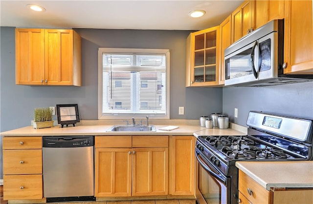 kitchen with stainless steel appliances, recessed lighting, light countertops, glass insert cabinets, and a sink