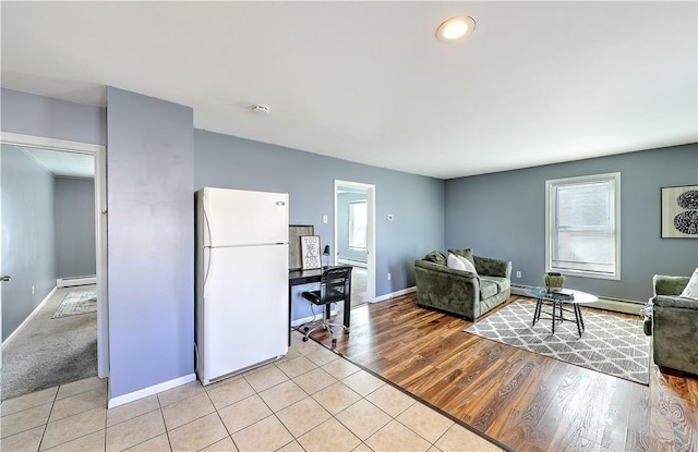 living area with light wood-type flooring, a baseboard radiator, baseboards, and baseboard heating