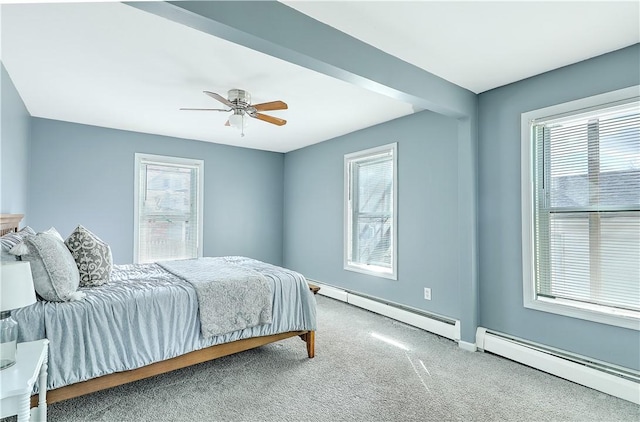 carpeted bedroom with a baseboard heating unit, a baseboard radiator, multiple windows, and baseboards