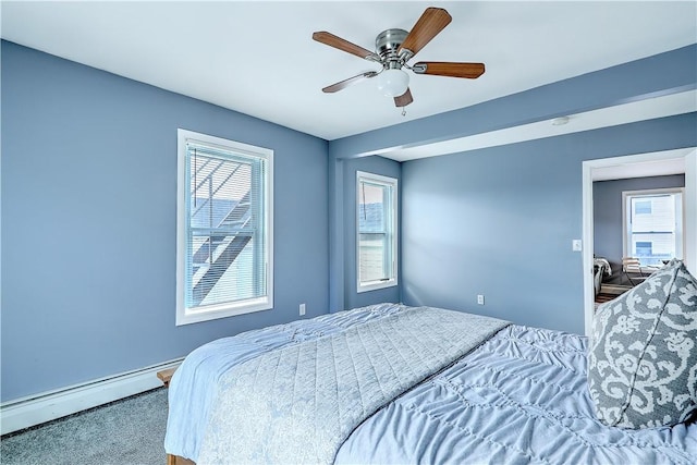 bedroom with ceiling fan, multiple windows, and baseboard heating