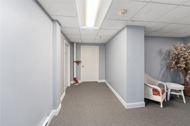 corridor with carpet floors, a paneled ceiling, and baseboards