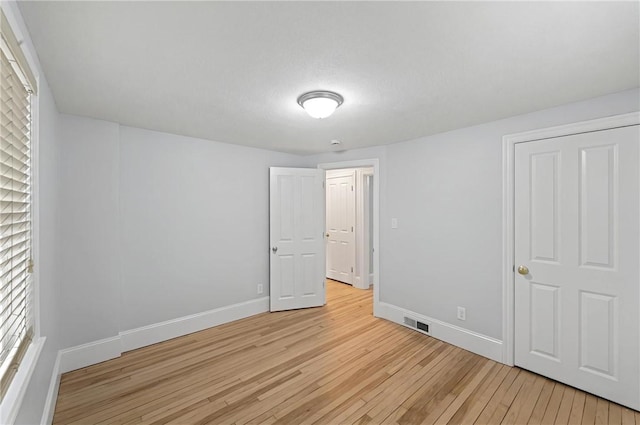 unfurnished bedroom featuring light wood-style floors, visible vents, and baseboards