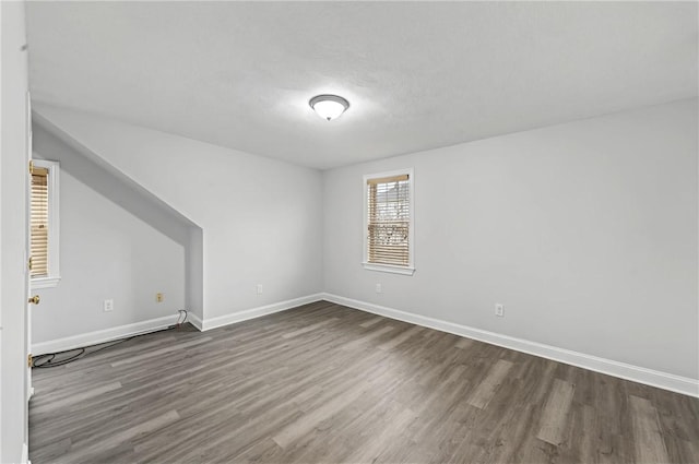 additional living space with baseboards and dark wood-style flooring