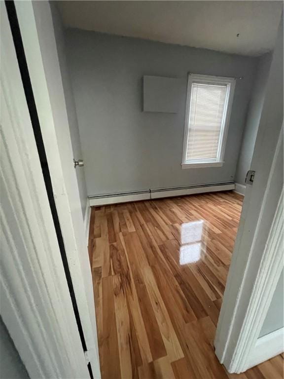 unfurnished bedroom featuring baseboards, baseboard heating, and wood finished floors